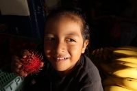 Viernes 8 de julio. Un niño de escasos 6 años de edad juega y se divierte con la lente fotográfica mientras que sus padres se dedican a la distribución del fruto del Rambután en la Central de Abastos de la ciudad de Tuxtla Gutiérrez. Este fruto es sembrad