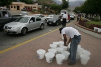 Un ciclista interrumpe a los trabajadores quienes reparten cubetas durante las celebraciones del Día Mundial del Agua para exigirles que sea regularizado el servicio de agua potable en el oriente de esta ciudad.